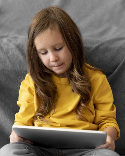 垂直小女孩在用平板电脑平板电脑青少年电子