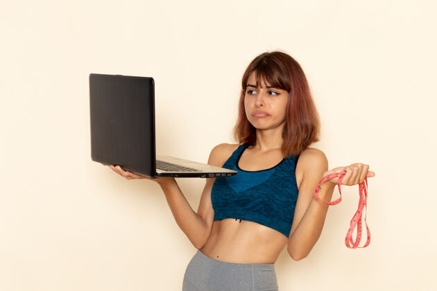 人年轻女性穿着蓝色衬衫 身体健康 在浅白墙上使用笔记本电脑的前视图前面身体性感