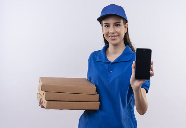 盒子身穿蓝色制服 戴着帽子的年轻送货女孩手里拿着一叠比萨饼盒 脸上露出自信的微笑披萨微笑自信