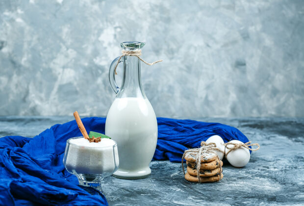 钙在深蓝色和灰色的大理石表面 合上一壶牛奶 配上蓝色围巾 巧克力片和白色饼干 还有一杯酸奶水平曲奇乳制品特写