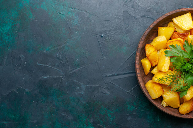 可食用水果俯视图深蓝色桌子上棕色盘子里的烤土豆片和绿色蔬菜芒果柑橘盘子