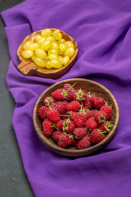 浆果顶视图树莓黄色葡萄碗紫色披肩在黑暗的表面葡萄披肩碗
