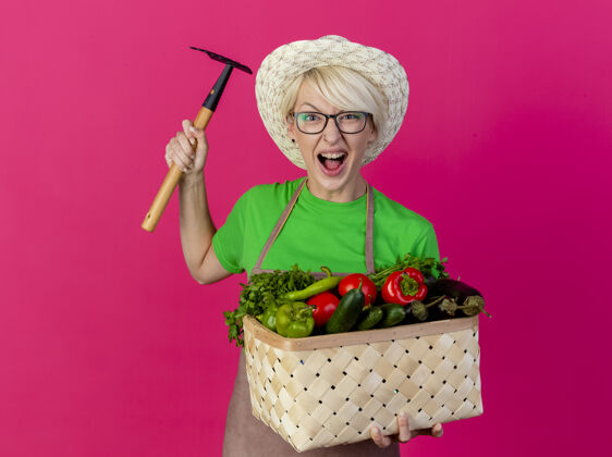 迷你一位年轻的园丁 围着围裙 戴着帽子 手里拿着装满蔬菜的箱子头发围裙女人