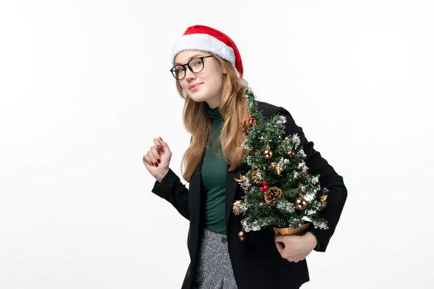 套装正面图年轻女性手持白色桌上的圣诞树玩具新年圣诞成年人风景微笑