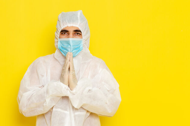 科学身穿白色特殊防护服 戴着面具的男性科学工作者在黄色墙上摆姿势的正面图特殊男性姿势