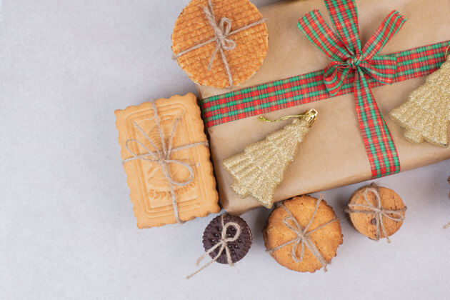 肉桂棒绳子里的甜饼和礼物 还有白色表面的圣诞金色玩具华夫饼食物可口