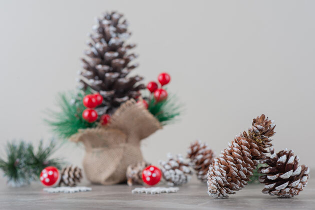 圣诞用冬青浆果和树枝装饰的松果放在大理石桌上松树冬天冬青树浆果