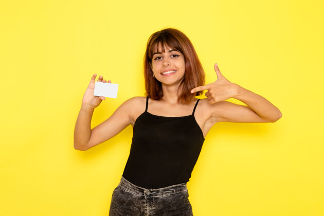女孩身穿黑色衬衫和灰色牛仔裤的年轻女性正拿着黄色墙上的塑料卡年轻前面性感
