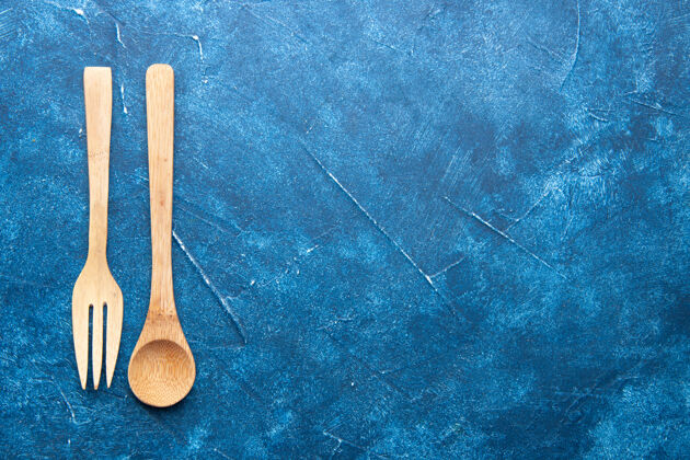 木材顶视图木制叉子勺子上的蓝色桌子与副本的地方勺子和叉子金属工具