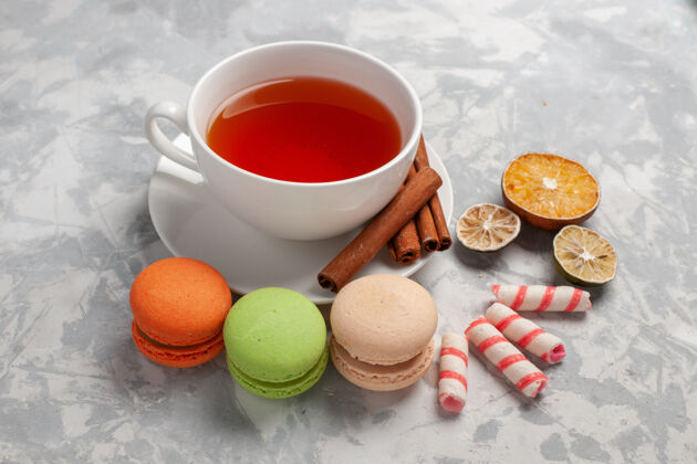 饮料前视图-一杯茶和法国马卡龙放在浅色的桌子上饮料茶容器