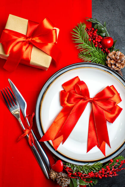 餐盘新年背景的特写镜头用红丝带在餐盘上餐具套装装饰配件杉木树枝旁边的一个红色餐巾纸礼物圣诞冷杉风景
