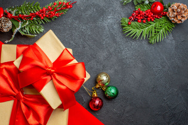 圣诞节圣诞背景与蝴蝶结形丝带和杉木枝装饰配件在一个黑暗的桌子上美丽的礼物树枝冷杉蝴蝶结