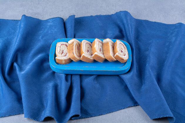 木材一块蓝色的木板 桌布上有甜的切片卷面包房烘焙卷