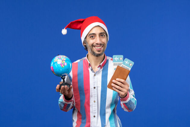 颜色前视图常规男性与门票和地球仪上的蓝色墙壁假日新年的颜色圣诞节成人视图