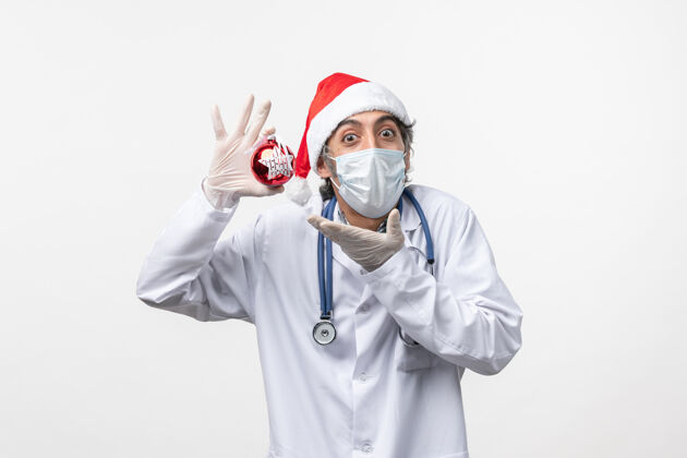 冠状病毒正面图白色地板上戴着玩具面具的男医生健康病毒共度新年实验室外套病毒医生