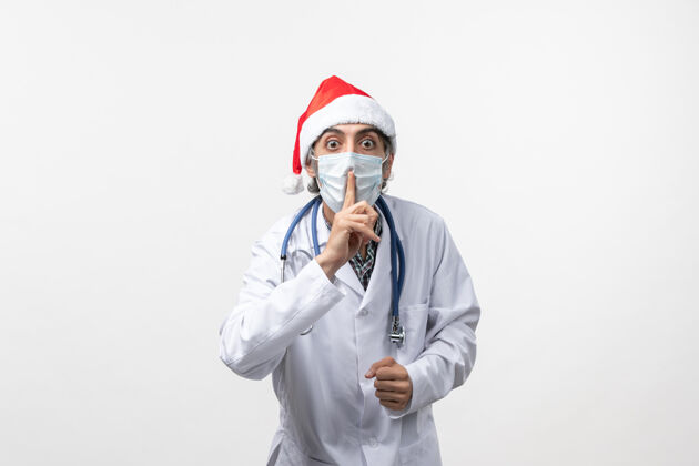 外套正面图白色办公桌上戴着口罩的男医生假日大流行病毒冠状病毒服装圣诞节