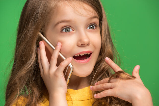 幸运快乐的少女站着 微笑着用手机在时尚的绿色工作室面部教育女士
