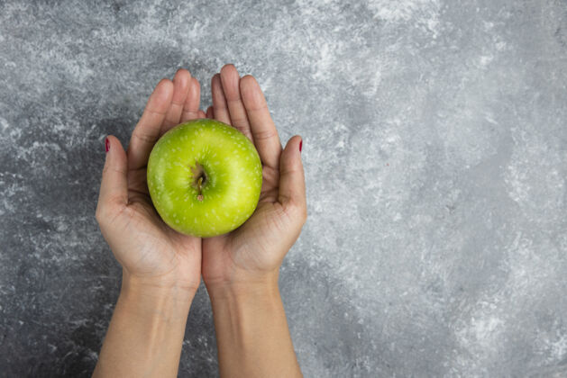 绿色双手放在大理石上拿苹果的女人美味多汁观点
