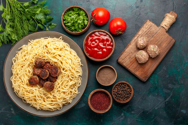 食物俯瞰煮熟的意大利面食 蓝色表面有肉丸和不同的调味品胡椒粉晚餐不同