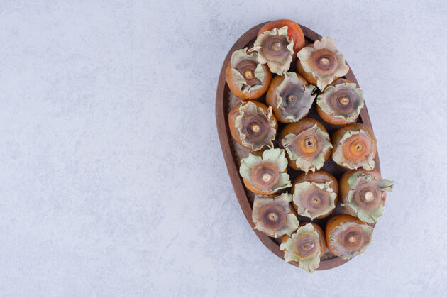 清淡在灰色表面的木制盘子里放上李子枣美味热带水果