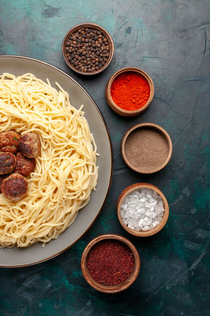 晚餐顶视图煮熟的意大利面食与肉丸和调味品在深蓝色的表面烹饪酱汁食物