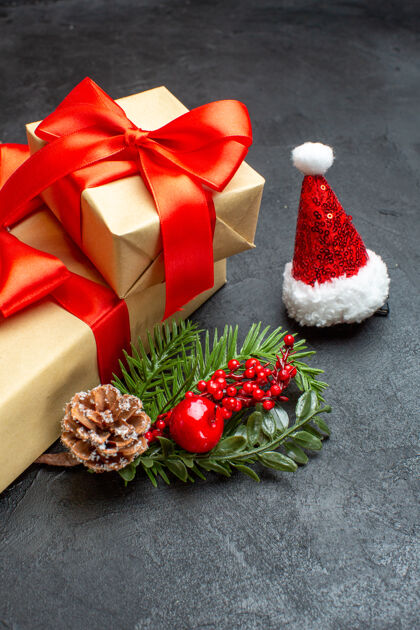 树枝圣诞心情与蝴蝶结形状的彩带和杉木枝装饰配件圣诞老人帽松树锥在黑暗的背景美丽的礼物前视图球果花束圣诞老人