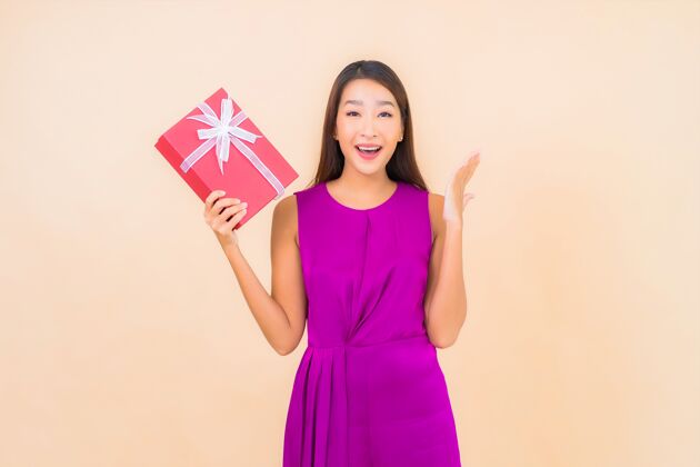 亚洲肖像美丽的亚洲年轻女子与红色礼品盒的颜色隔离的背景高兴礼物年轻