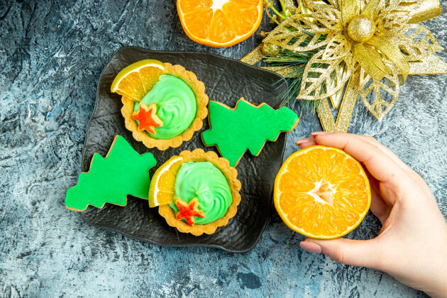 果汁俯视图小馅饼圣诞树饼干黑色盘子圣诞装饰品削减橙色在女性手中的灰色表酸的水果新鲜的
