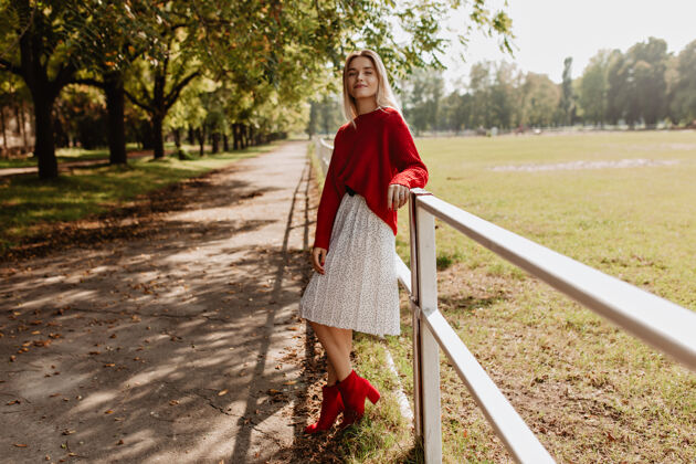 季节美丽的金发女郎在秋天的公园里穿着时髦的红衣服穿着白裙子的漂亮女孩在户外玩得很开心户外成人明亮