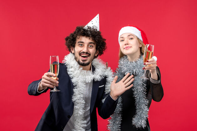 服装前视图年轻夫妇庆祝新年红墙圣诞爱情假期肖像微笑年轻夫妇
