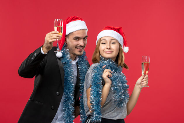 成人前视图年轻夫妇刚刚在红墙爱心圣诞派对上庆祝新年帽子肖像服装