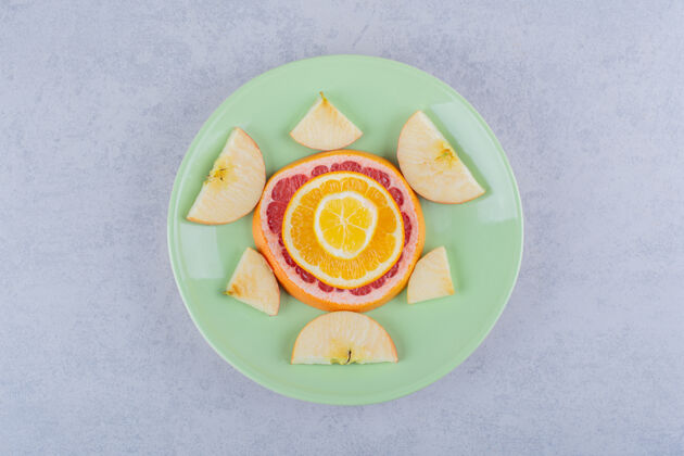 多汁把新鲜的葡萄柚片 橘子片 柠檬片和苹果片放在绿色的盘子里食用柑橘圆形