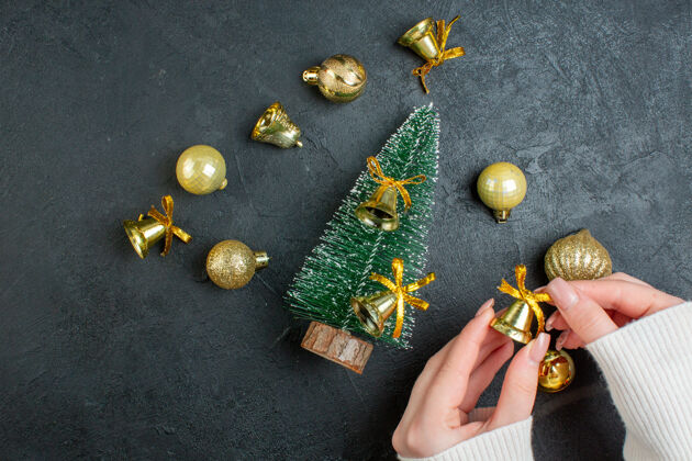 头顶手持装饰配件礼品盒和圣诞树在黑暗的背景俯视图扣扣件刀