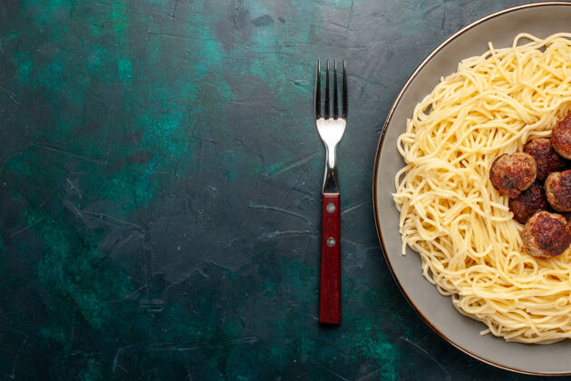 盘子在深蓝色的桌子上俯瞰煮熟的意大利面食和肉丸意大利面食物意大利面沙司