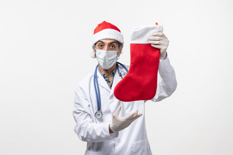 成人正面图男医生拿着大节日袜子在白墙上乔维德病毒度假圣诞节男医生视图