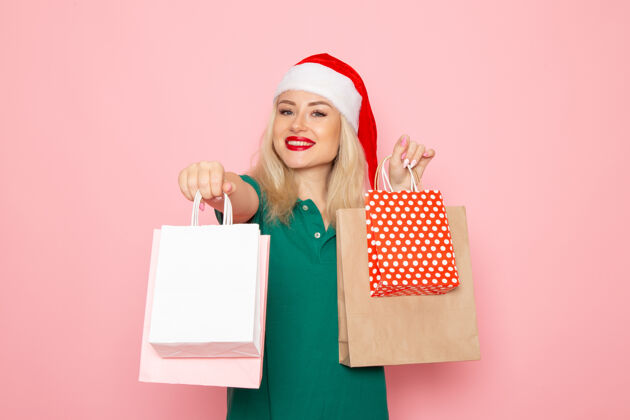 年轻女性正面图：年轻女性拿着包装好的圣诞礼物站在粉色墙上 圣诞照片模特新年假期包装圣诞节漂亮