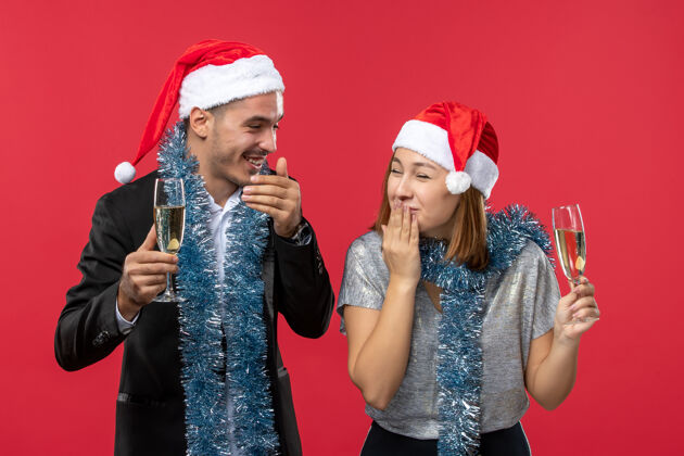成人正面图：年轻夫妇在红桌上庆祝新年 爱的圣诞派对饮料微笑书桌庆祝