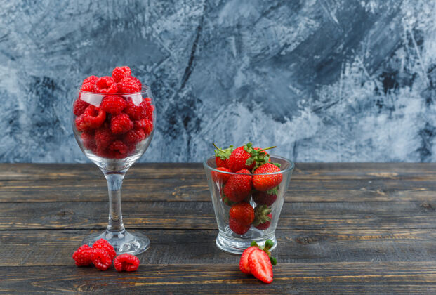 甜味草莓和覆盆子放在玻璃容器里深色路径浆果