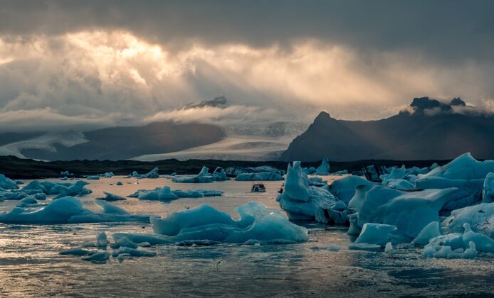 冬天美丽的约克萨隆冰川泻湖在冰岛 阳光从黑暗多云的天空横梁自然冰