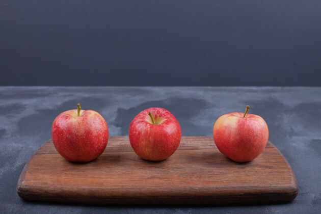 生成熟的红苹果在蓝色的表面木材多汁酸
