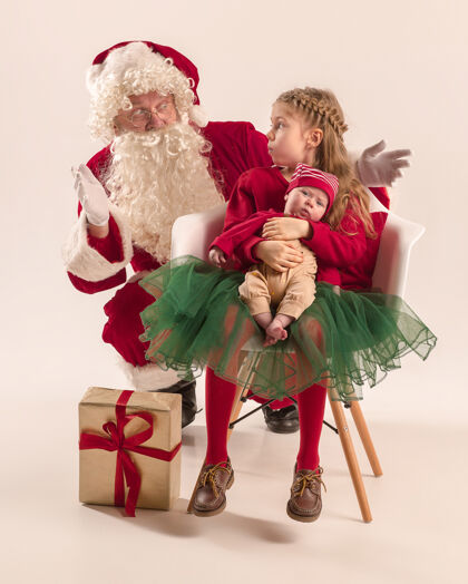 毯子可爱的新生小女婴和漂亮的妹妹穿着圣诞服装和圣诞老人的服装和帽子的男子圣诞画像脸男人肖像