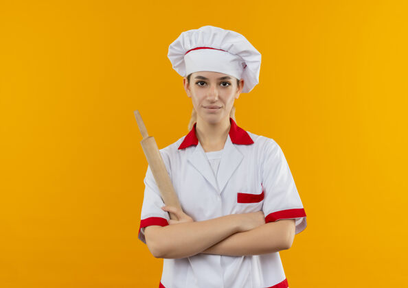 烹饪年轻漂亮的厨师穿着厨师制服 站在橙色的空间里 抱着擀面杖 姿势封闭厨师橙色手持