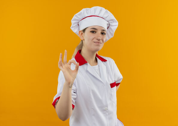 制服很高兴年轻漂亮的厨师穿着厨师制服 在橙色的空间里看起来很孤立招牌烹饪漂亮