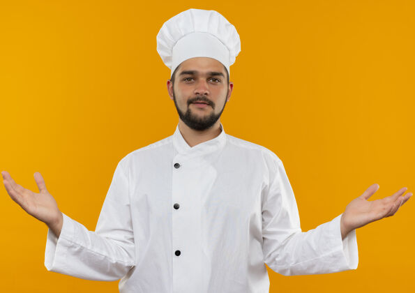 厨师身着厨师制服的年轻男厨师很高兴 双手空空荡荡 在橙色的空间里显得孤立无援看空显示