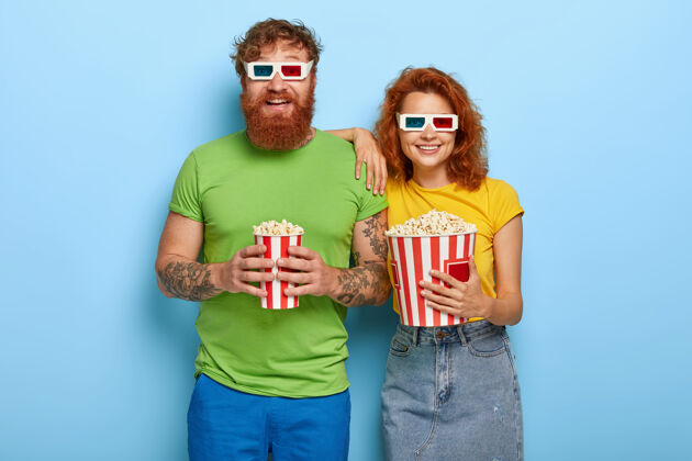 男朋友快乐的姜女和留着胡子的丈夫在晚上的表演中来到电影院的一个孤立镜头 有着愉快的面孔和微笑 戴着立体眼镜 一边看电影一边吃着美味的小吃娱乐乐观丈夫