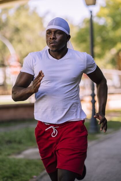 形状一个穿着白衬衫的非裔美国男子在公园里白天慢跑的垂直镜头衬衫能量衣服