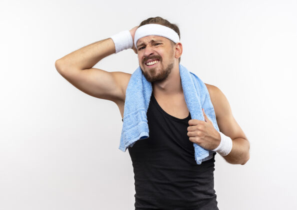 头疲惫的年轻英俊的运动型男子戴着头带和腕带 手放在头上 脖子上拿着毛巾 隔离在白色的空间里手戴着毛巾