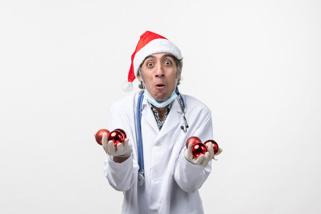 圣诞节正面图白色地板上拿着玩具的男医生-健康病毒情感制服冠状病毒微笑