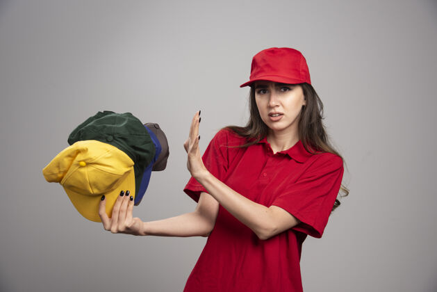 帽子穿红色制服的女送货员远离彩色帽子女工作工人