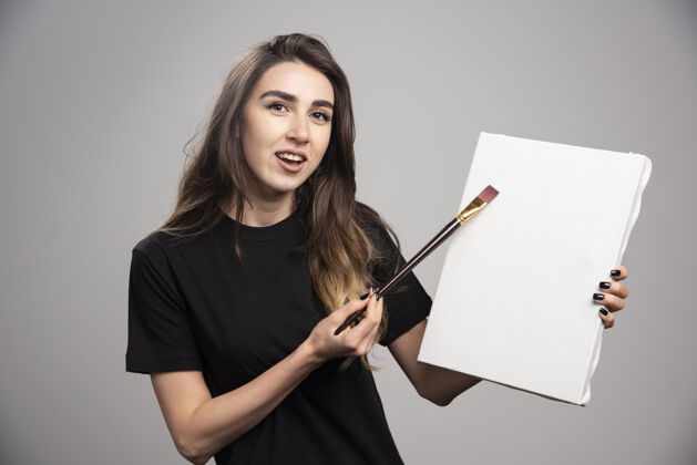 女人在画布上画黑色衬衫的女艺术家艺术家年轻人表演